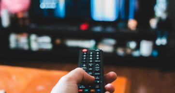 Person holding a remote, watching tv